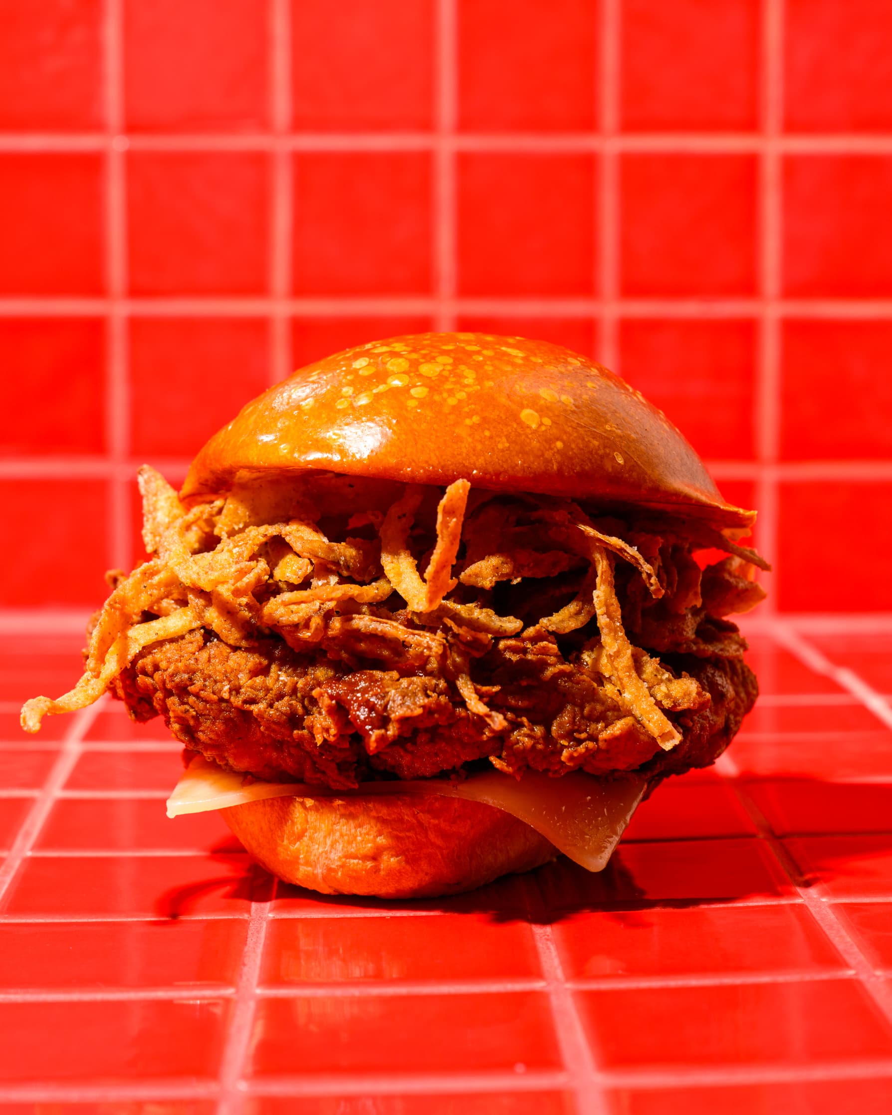 Close-up of a fried chicken sandwich topped with crispy onion rings