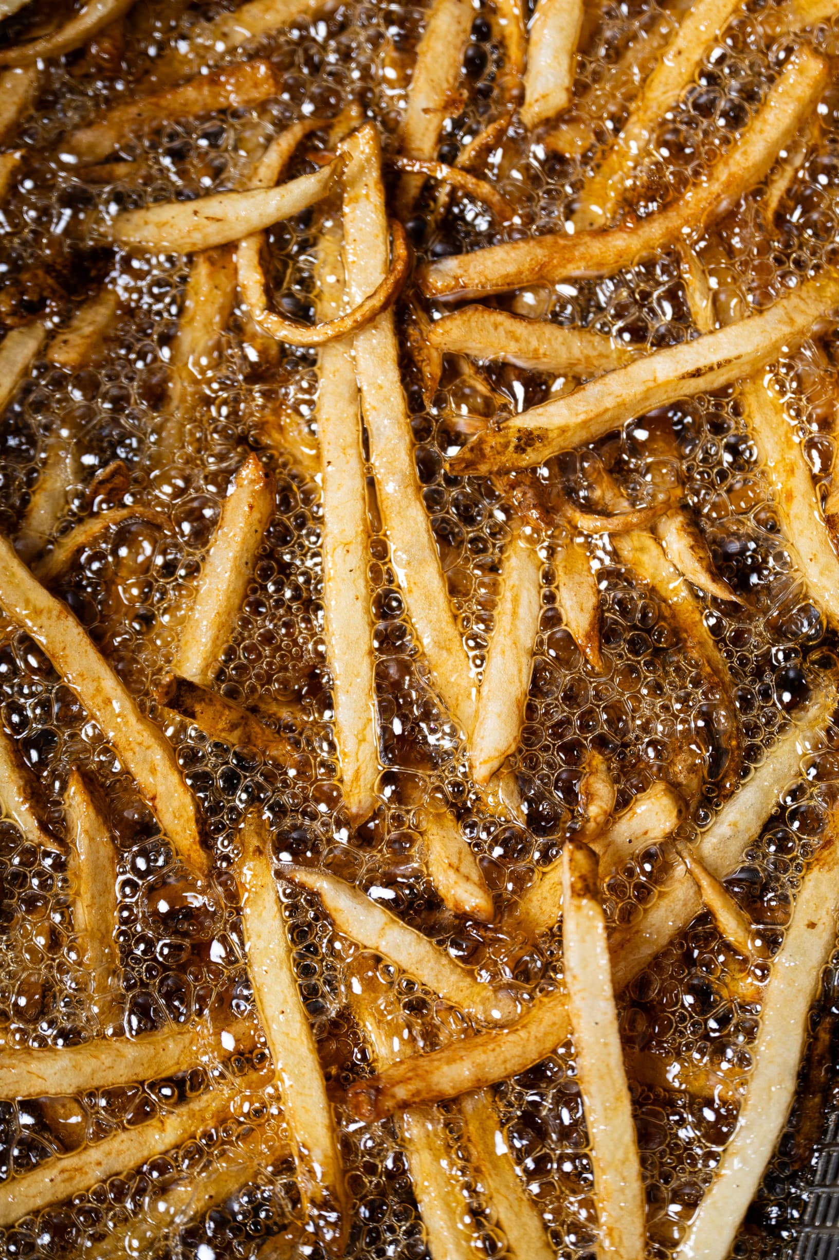 Fries submerged in hot beef tallow inside the fryer